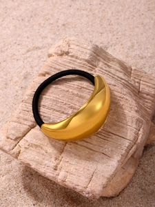 Close-up of golden crescent moon hair cuff with black elastic band on natural stone