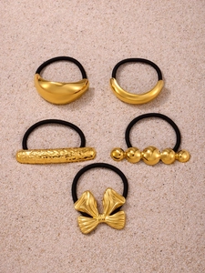 Detailed view of 5-piece gold metal hair ties with crescent and bow designs