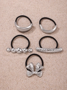 Detailed view of silver metal charms on black elastic hair ties with textured background