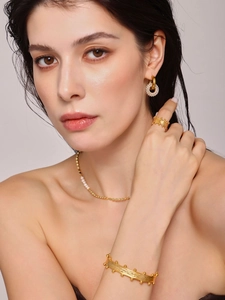 Detailed view of textured gold jewelry set with pearl necklace and brushed metal ring