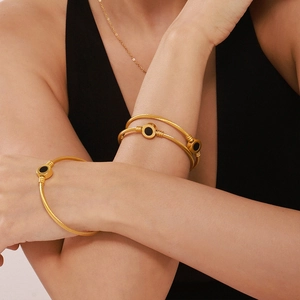 Bracelet jonc en câble d'acier doré avec des charmes ronds noirs en nacre naturelle