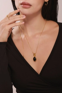 Détail d'un collier doré de style français avec un pendentif carré en onyx noir poli