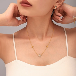 Golden four-leaf flower necklace set with cubic zirconia on a model, 18K gold plated finish