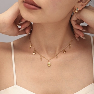 Polished 18K gold plated necklace with heart and horn charms on a female model