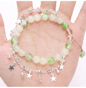 Dettaglio di un bracciale a due strati con perline e stelle tenuto nel palmo