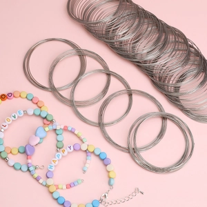 Stack of silver memory steel wire coils and DIY beaded bracelets with heart charms