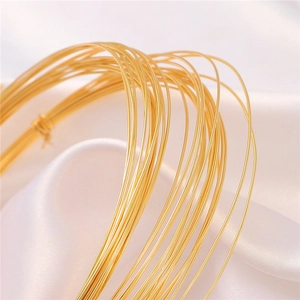 Roll of 18K gold-plated copper wire for DIY jewelry making on white satin fabric