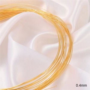 Macro shot of 0.4mm 18K gold-plated jewelry wire on elegant white silk background
