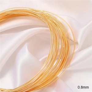 Macro shot of 0.8mm gold-plated copper wire for DIY jewelry on white silk fabric