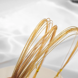 18K vergoldete strukturierte Metalldrähte für DIY-Schmuck auf weißem Seidenhintergrund