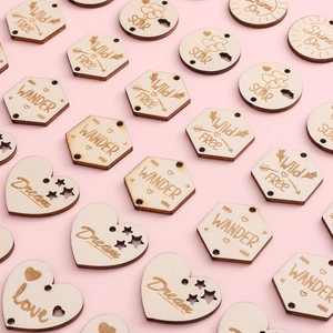 Laser cut wooden pendants with inspirational words like Dream and Wander on pink background