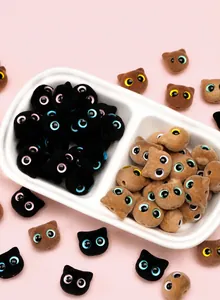 Close-up of cute flocked cat head beads in brown and black for DIY jewelry making