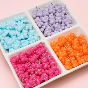 Colorful acrylic bear pendants with metal rings for DIY jewelry making on white tray