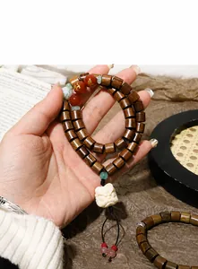 Detailopname van houten kralenarmband met gegraveerde rode kraal en dierenhanger