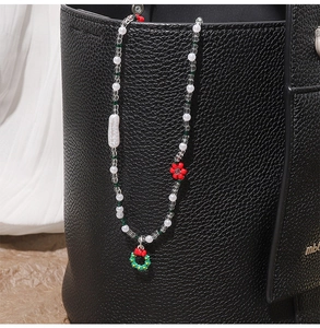 Beaded Christmas necklace with festive wreath pendant hanging on a black leather bag