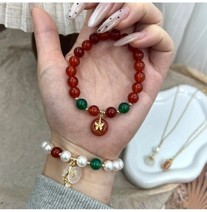 Detailed view of Chinese style beaded bracelets with red agate, pearls and lucky pendants