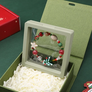 Detail of Christmas DIY beaded bracelet with star and tree charms in a floating frame