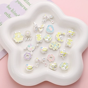 Assorted DIY enamel charms with butterflies and hearts in a floral ceramic dish