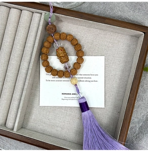 Detailed view of Rudraksha seed beads with carved figurine and silk tassel accessory