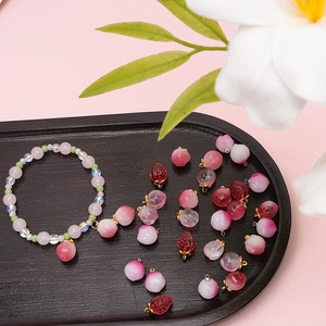 Ciondoli in vetro a fragola e pesca su bracciale con elegante sfondo floreale e rosa
