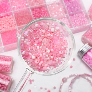 Mix of pink DIY jewelry beads in a glass spoon with storage box for handmade necklaces