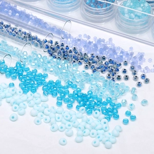 Detail of assorted blue glass seed beads spilling from a glass tube on white background