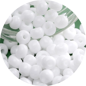 White glass seed beads for DIY jewelry making displayed on a green textured background