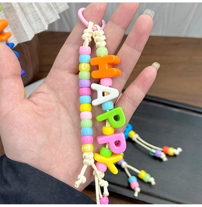 Dettaglio di perline colorate in acrilico fai-da-te e portachiavi con ciondolo Happy