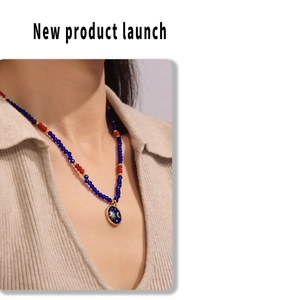 Dettaglio della collana di perline con cristalli blu e rossi e ciondolo sole luna