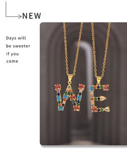Détail des pendentifs lettres W et E avec zircons colorés sur des chaînes dorées