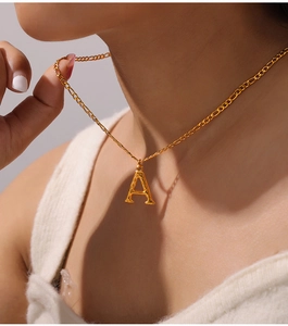 Detail of gold letter A pendant with brushed texture on a stylish Figaro chain necklace