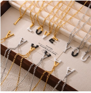 Detail of luxury titanium steel letter pendants with enamel finish on a jewelry tray