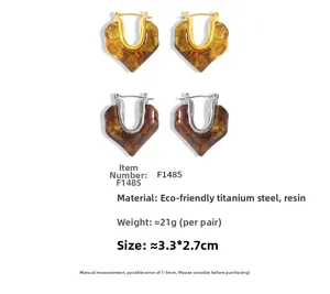 Dettaglio di orecchini a cuore in resina ambra e marrone con placcatura oro 18k