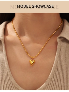 Présentation d'un collier pendentif cœur doré avec des détails de chaîne à micro billes