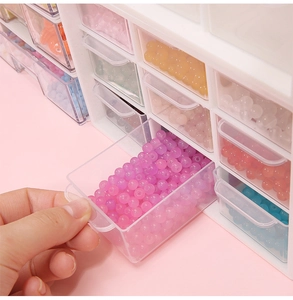 Detail of hand pulling an acrylic mini drawer filled with colorful craft beads