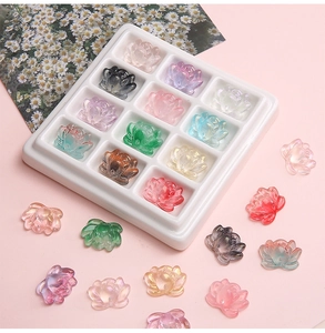 Detailed close-up of colorful 21mm glass lotus charms in a white grid tray for DIY jewelry