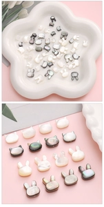 Vista macro de cuentas de concha natural con forma de conejo y gato para joyería DIY