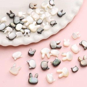 Cuentas de nácar natural con forma de conejo y gato para joyería DIY en plato blanco