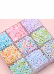 Détail macro de perles en verre givré pastel rangées dans une boîte de rangement plastique