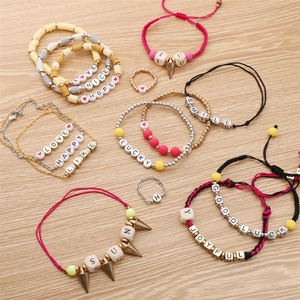 Vista superior de pulseras y anillos de cuentas DIY con letras y cuentas de arcilla