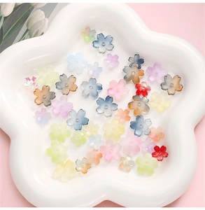 Vue détaillée de perles fleurs de cerisier en résine colorée dans un plat blanc pour DIY