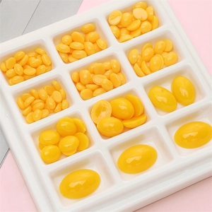 Yellow acrylic oval doll eyes in multiple sizes organized in a white grid tray