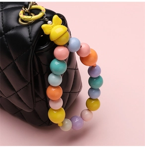 Detail of colorful macaron bead keychain with yellow bow on black quilted leather bag