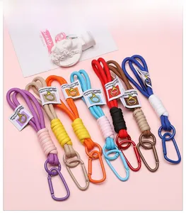 Set of 7 colorful braided keychains with metal carabiner and brand tags on pink background