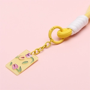 Handwoven yellow lanyard keychain with tulip pendant and metal ring on pink background