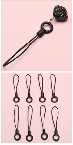 Detail view of black poodle-shaped phone charms with pearl finish and woven lanyards