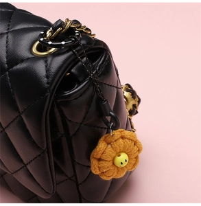 Detailed view of black quilted leather texture and woven flower charm on a handbag