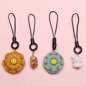 Handmade woven flower and cute bear phone charms with black lanyards on pink background