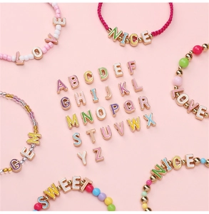 Bunte Emaille-Buchstabenperlen und DIY-Armbänder auf einem rosa Hintergrund arrangiert