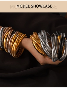 Nahaufnahme gestapelter Tubogas-Armbänder in Gold und Silber auf schwarzem Stoff